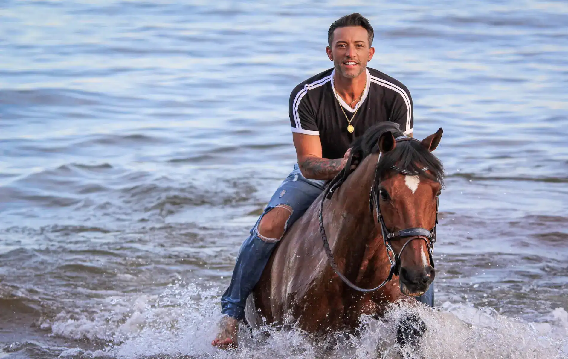 Jared riding brown horse through ocean waves